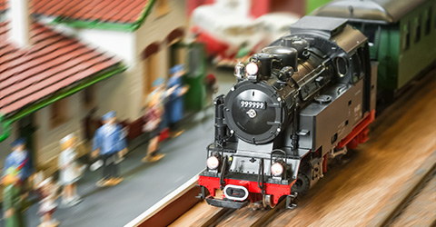 model train engine speeding through a miniature village with people watching vibrant scenery and three-dimensional features