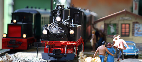model train scene with detailed figures and a vintage station depicting a lively miniature world featuring eight figures and a train